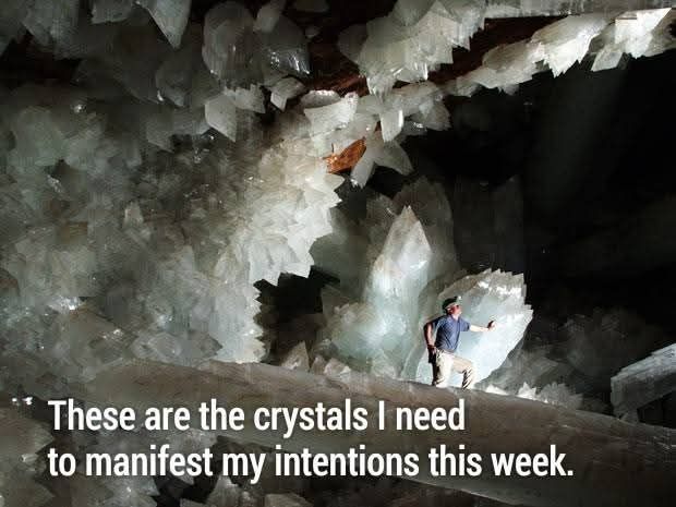 Man saying, "These are the crystals I need to manifest my intentions this week." He is in a cave with crystals twice his size.
