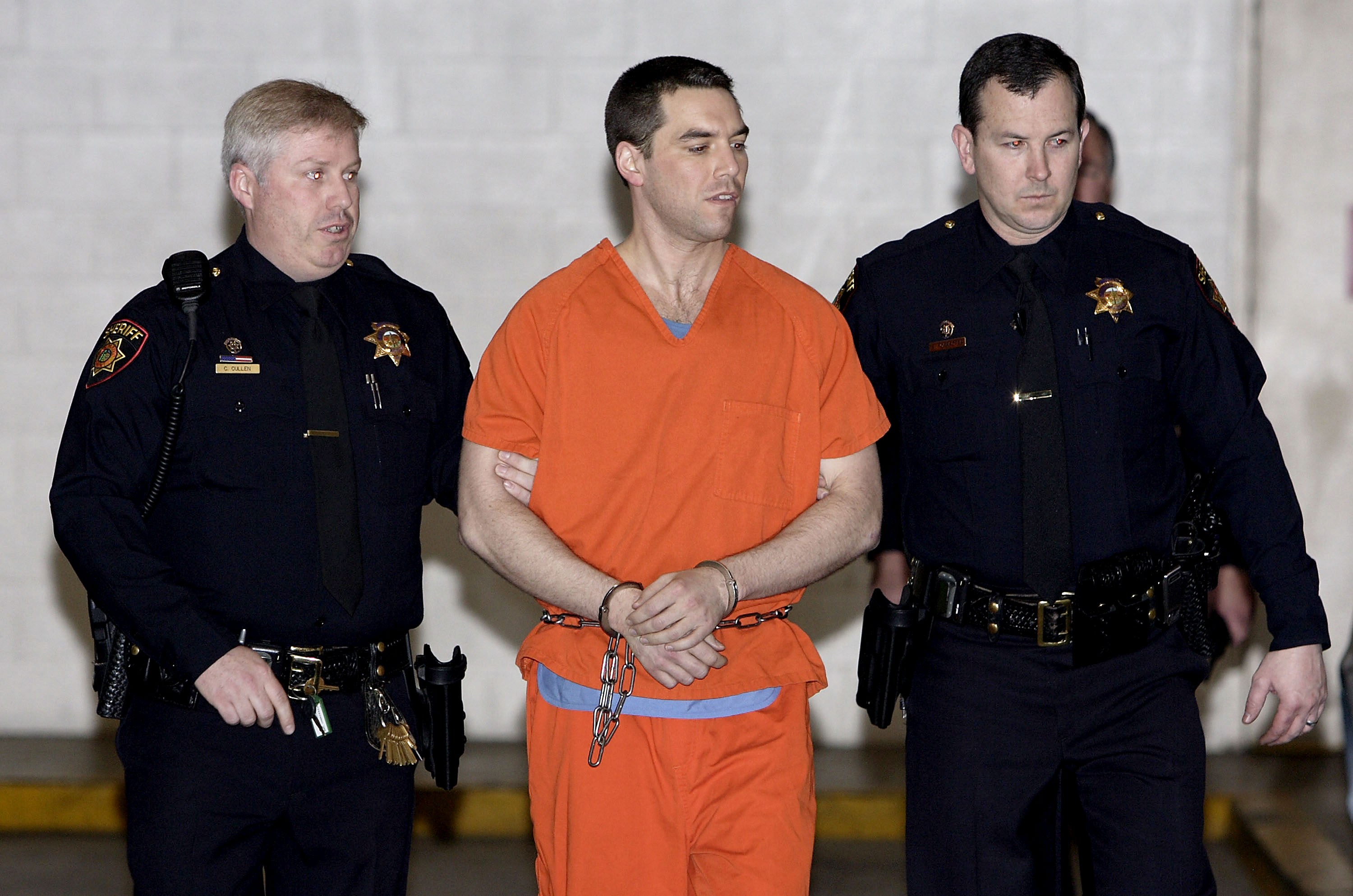 REDWOOD CITY, CA - MARCH 17: Convicted murderer Scott Peterson is escorted by two San Mateo County Sheriff deputies as he is walked from the jail to an awaiting van March 17, 2005 in Redwood City, California. Scott Peterson was transported to San Quentin Prison death row after he was formally sentenced to death for the murder or his wife Laci and their unborn son. (Photo by Justin Sullivan/Getty Images)