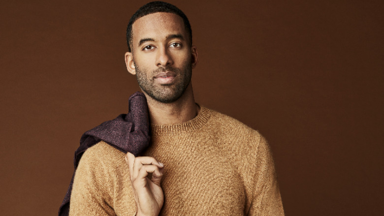 Matt James holding a coat over his shoulder