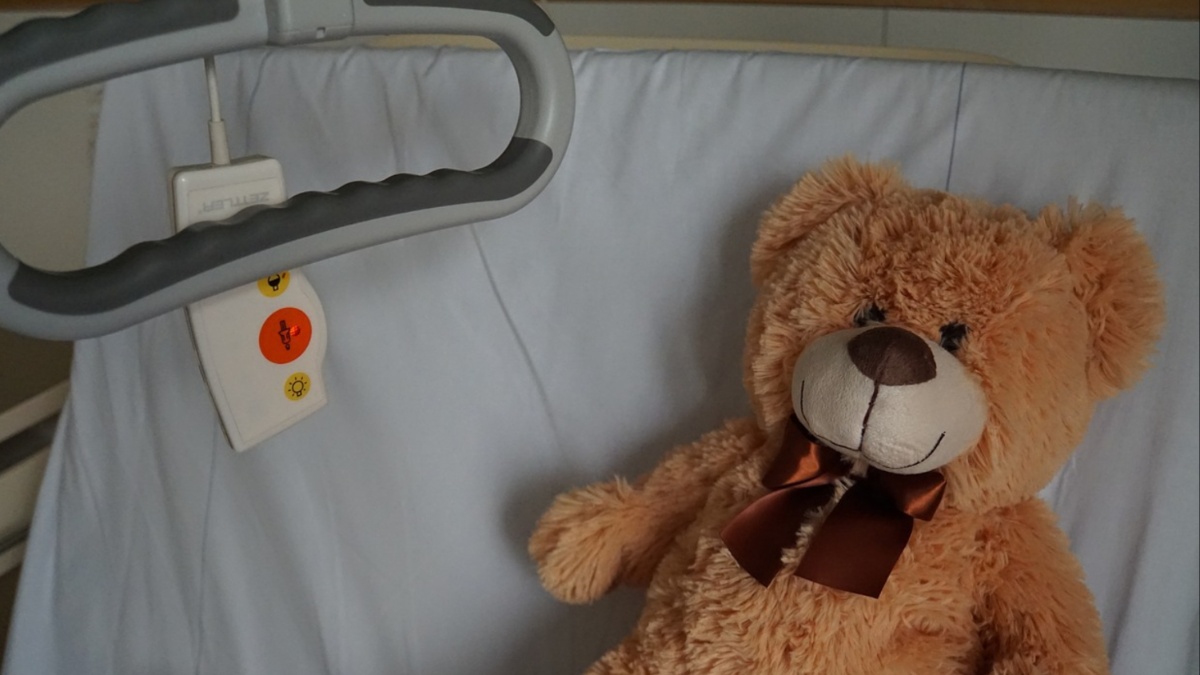 A teddy bear in a hospital bed.
