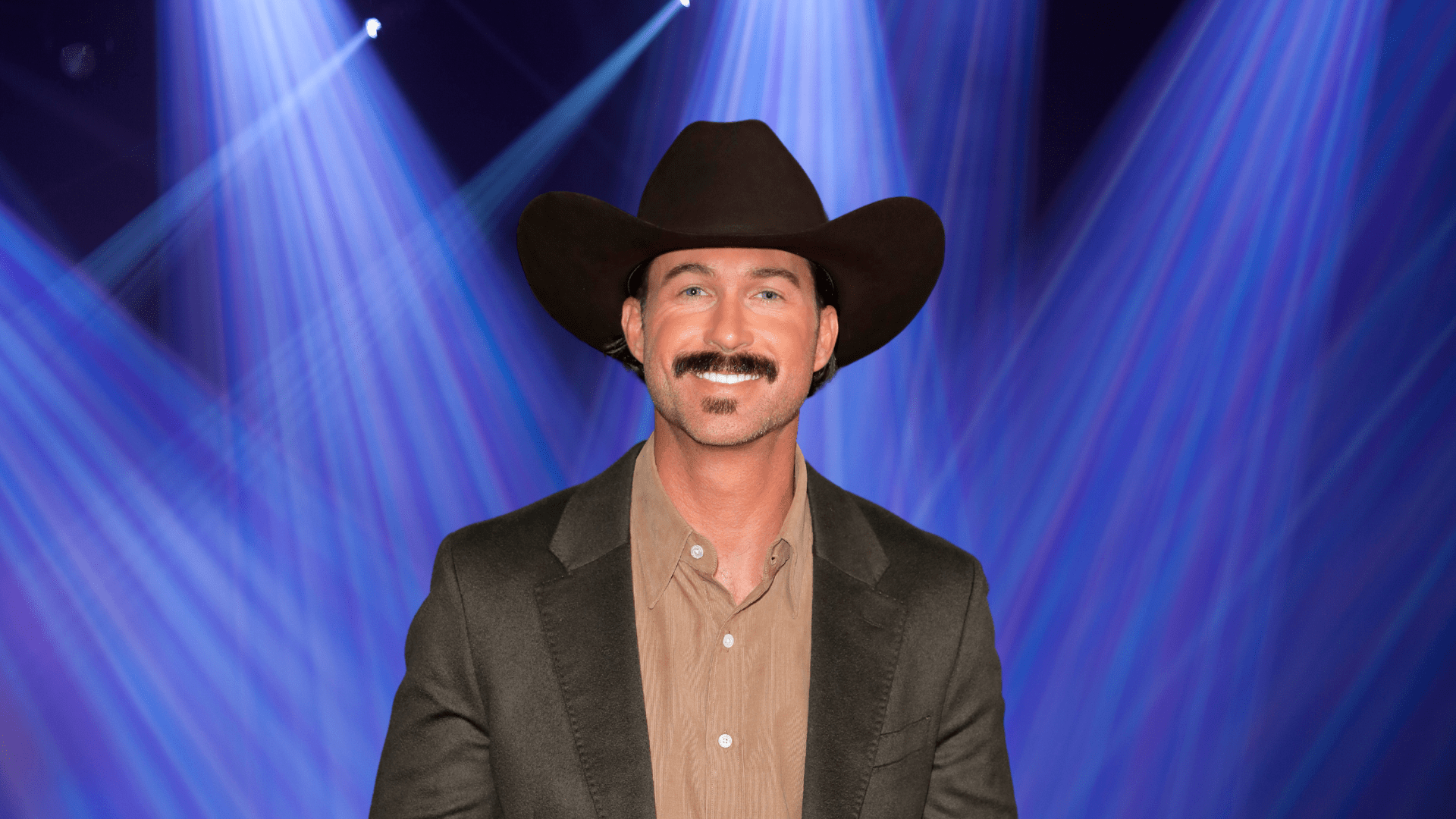 Riley Green wears a cowboy hat and smiles