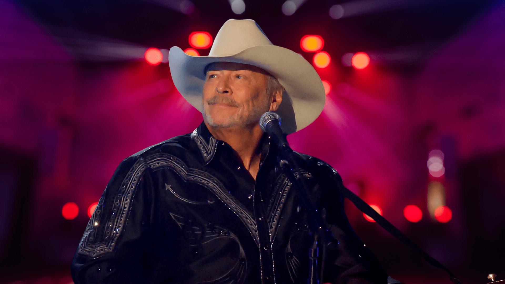 Alan Jackson standing behind a microphone