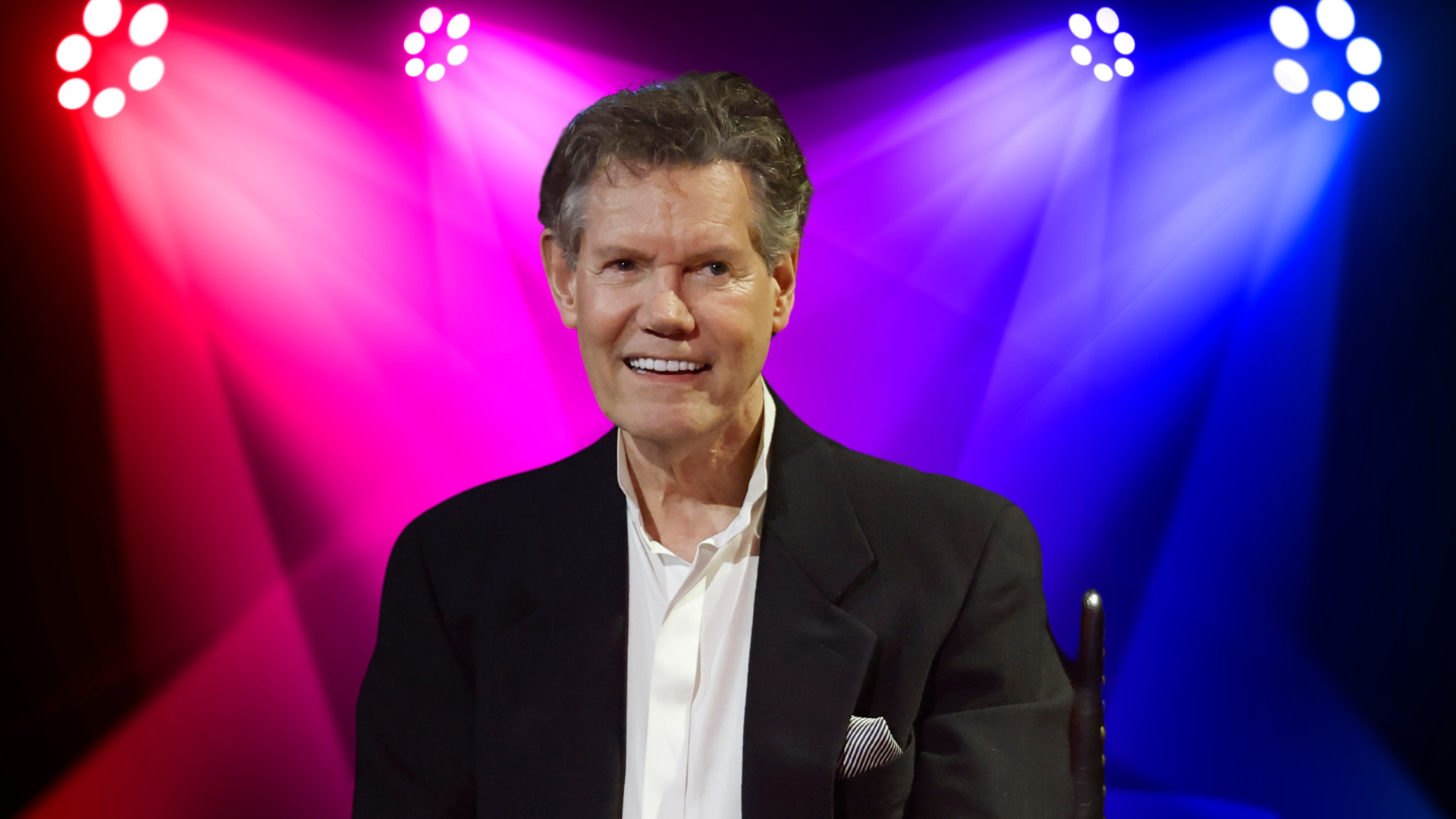 Randy Travis smiling on a stage