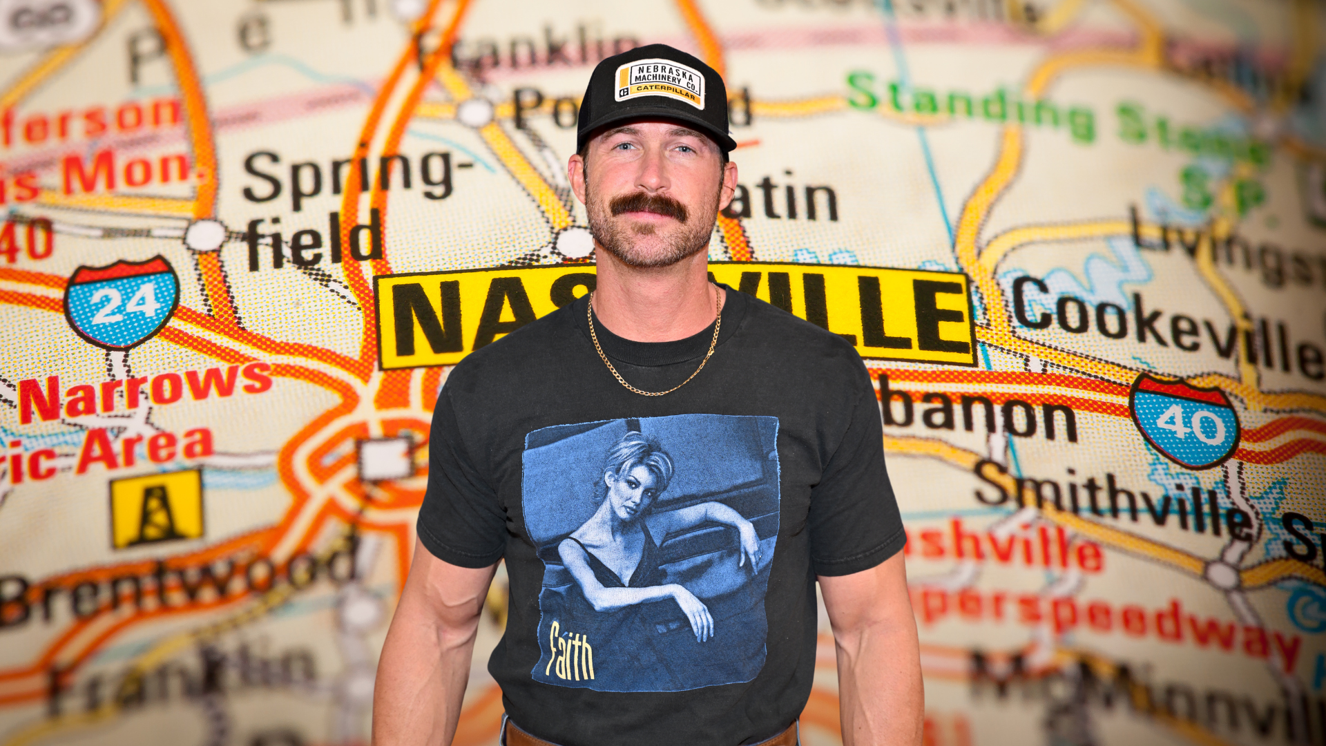 Riley Green posing in a Faith Hill t-shirt
