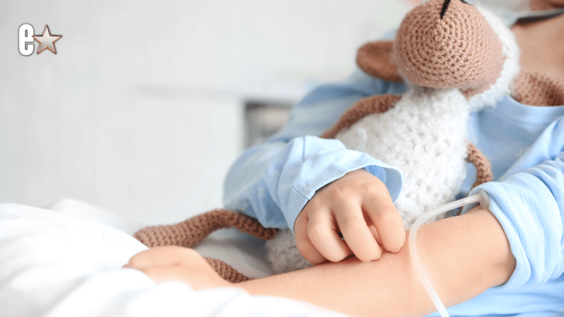 A child in a hospital holding a stuffed animal.