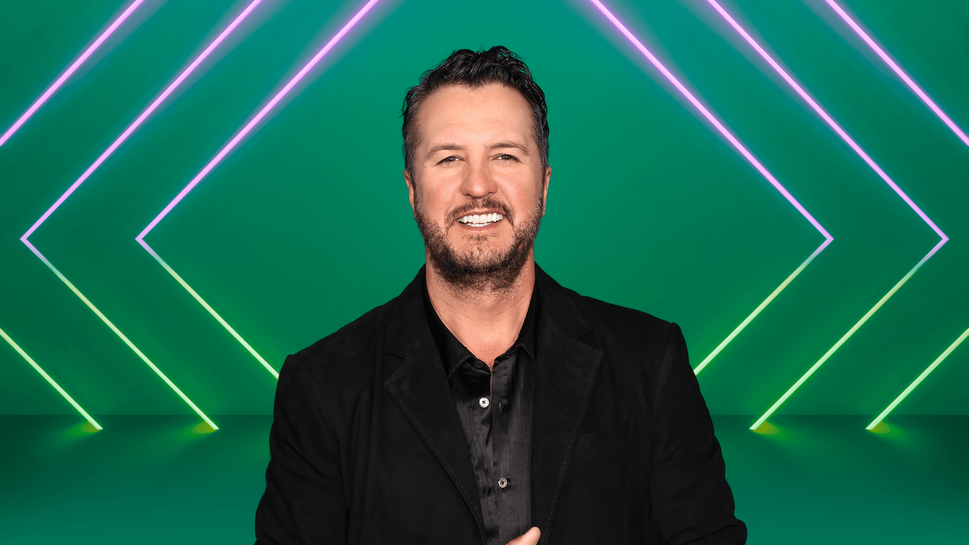 Luke Bryan smiling on a colorful stage