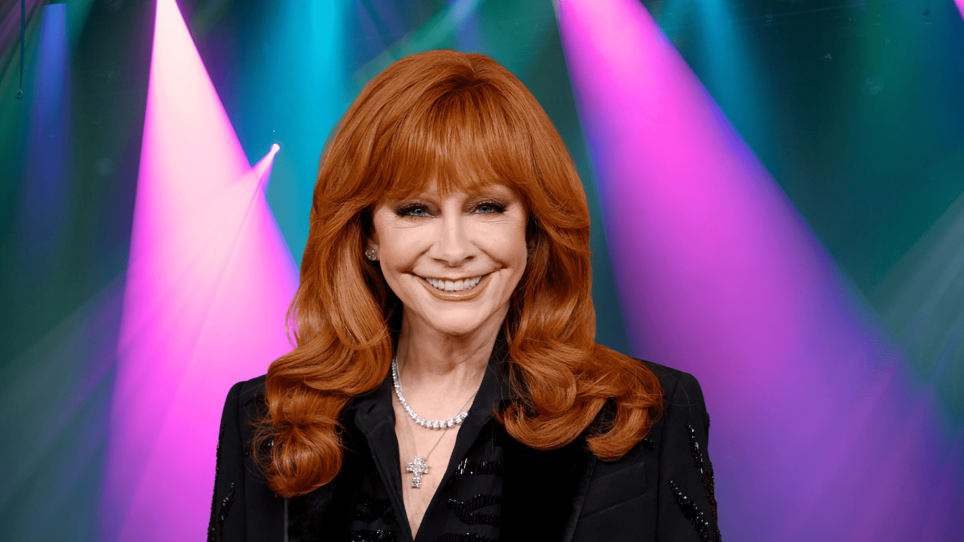 Reba McEntire smiling in a black jacket.