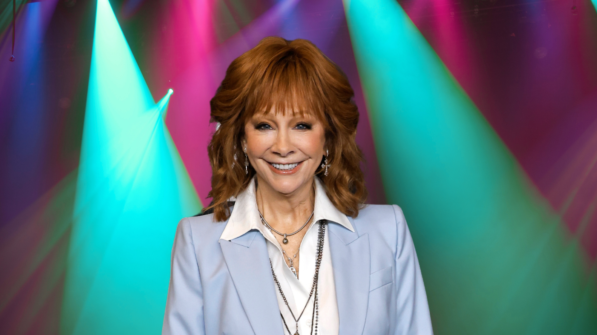 Reba McEntire smiling in front of colorful lights