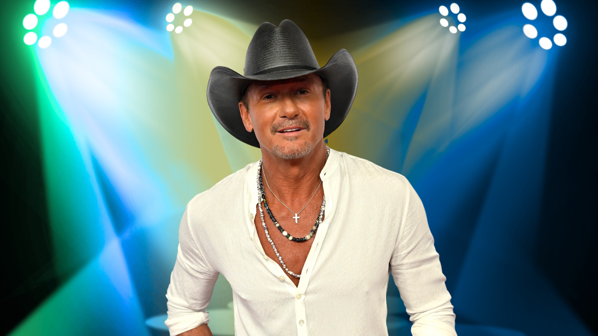 Tim McGraw smiling in front of colorful lights.