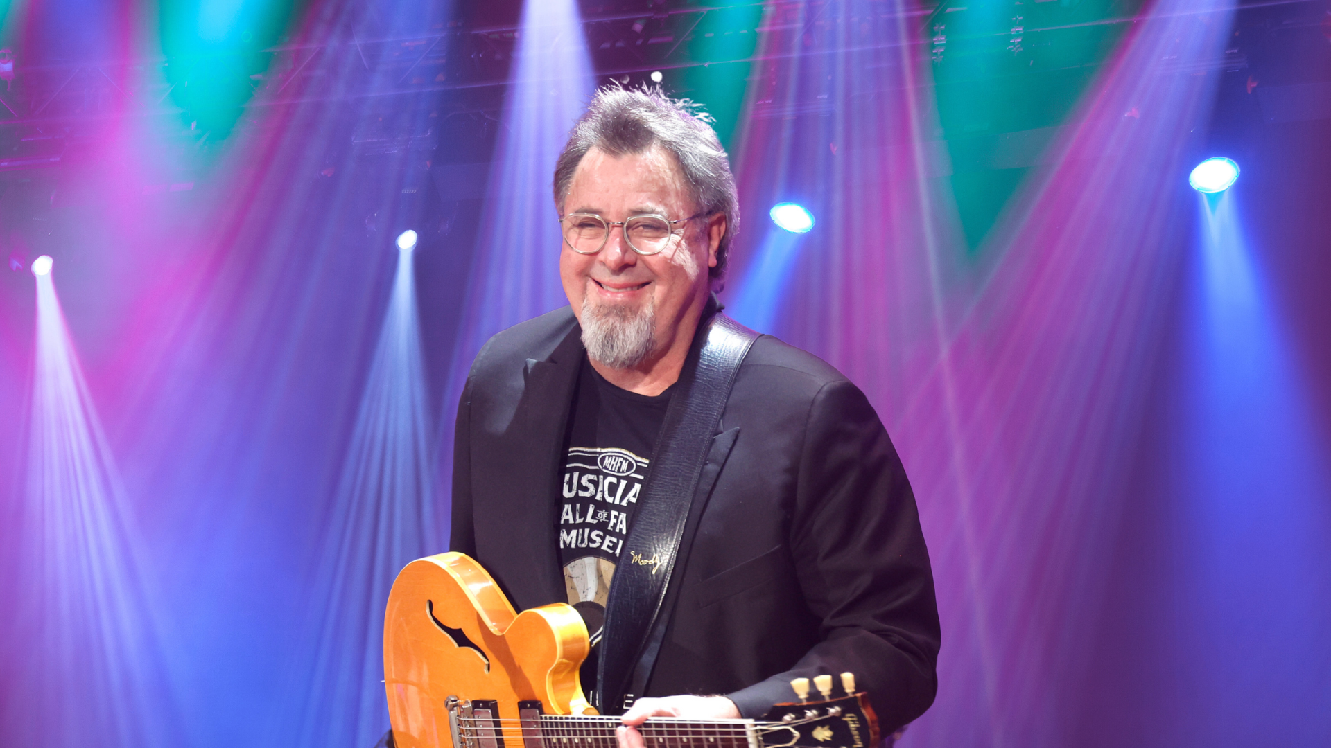 Vince Gill smiling with a guitar.