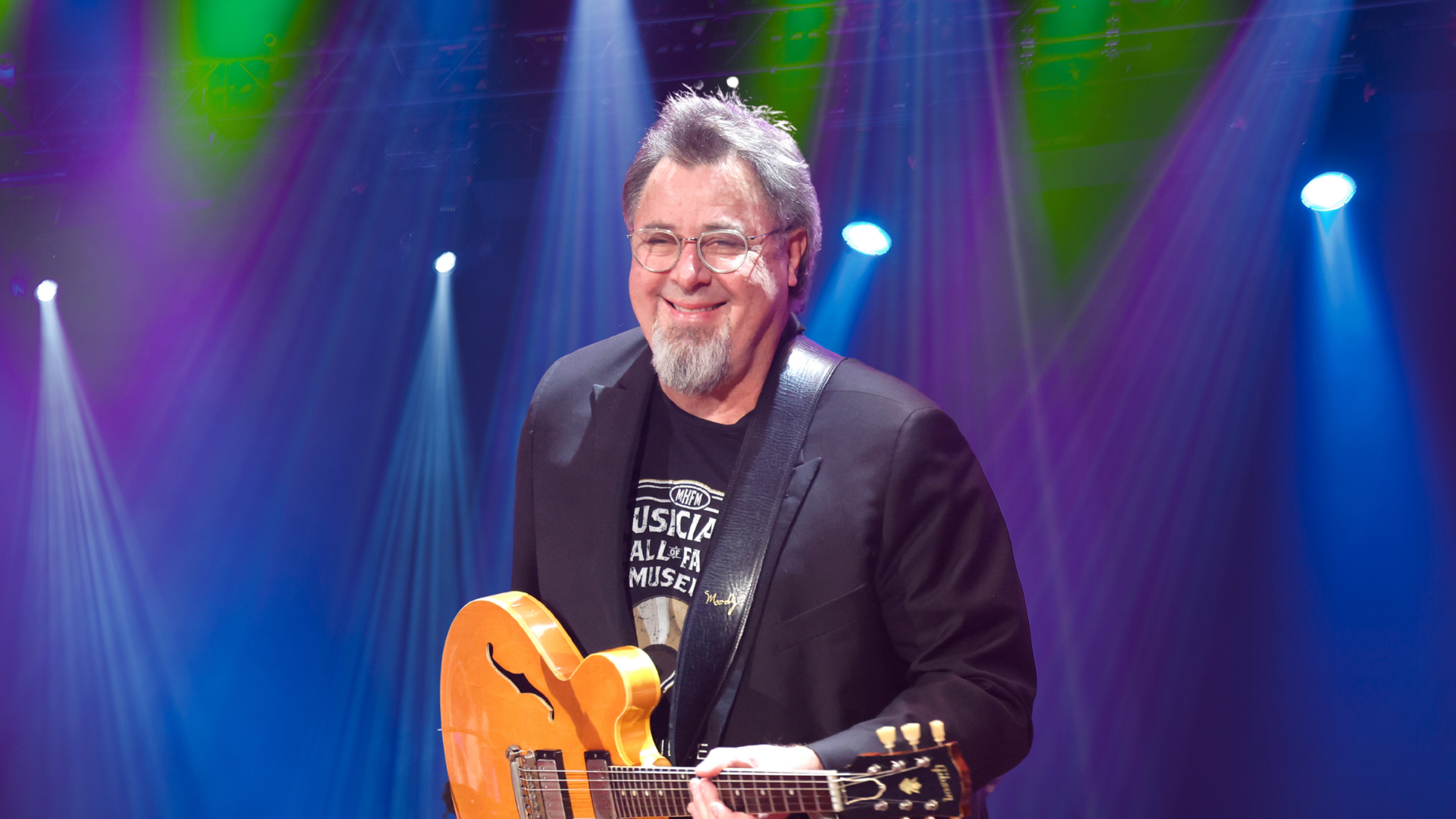Vince Gill holding a guitar on stage