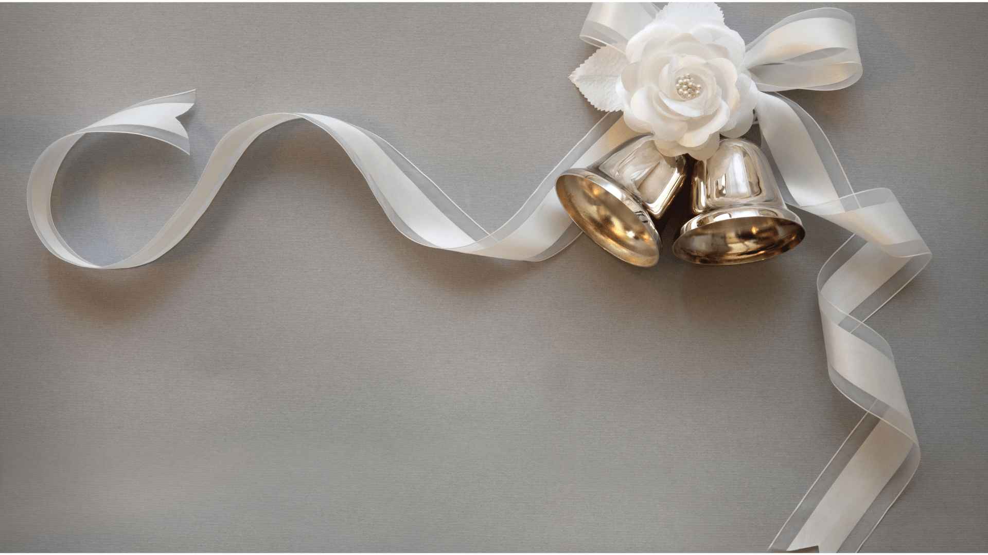 Two gold bells attached to a long ribbon tied into a bow