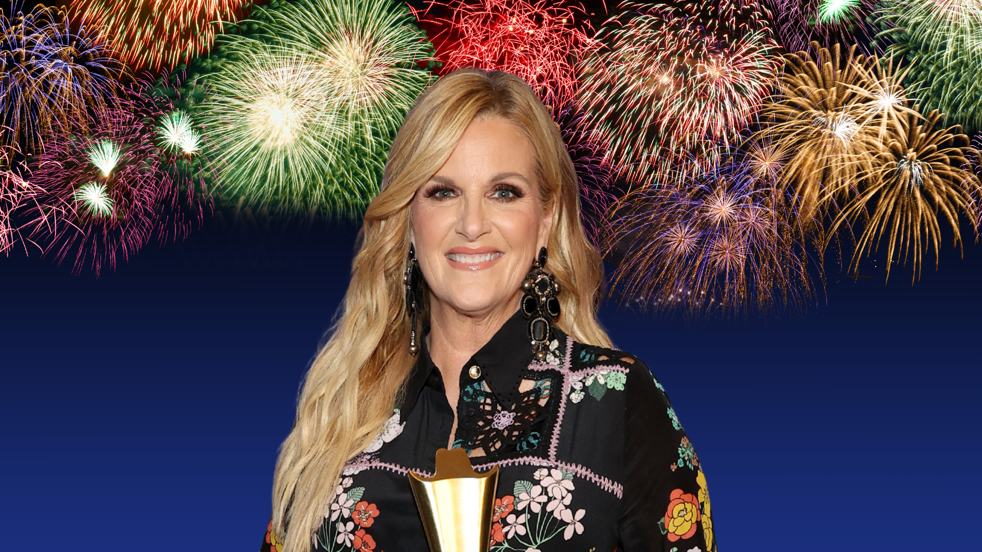 Trisha Yearwood posing with fireworks behind her.
