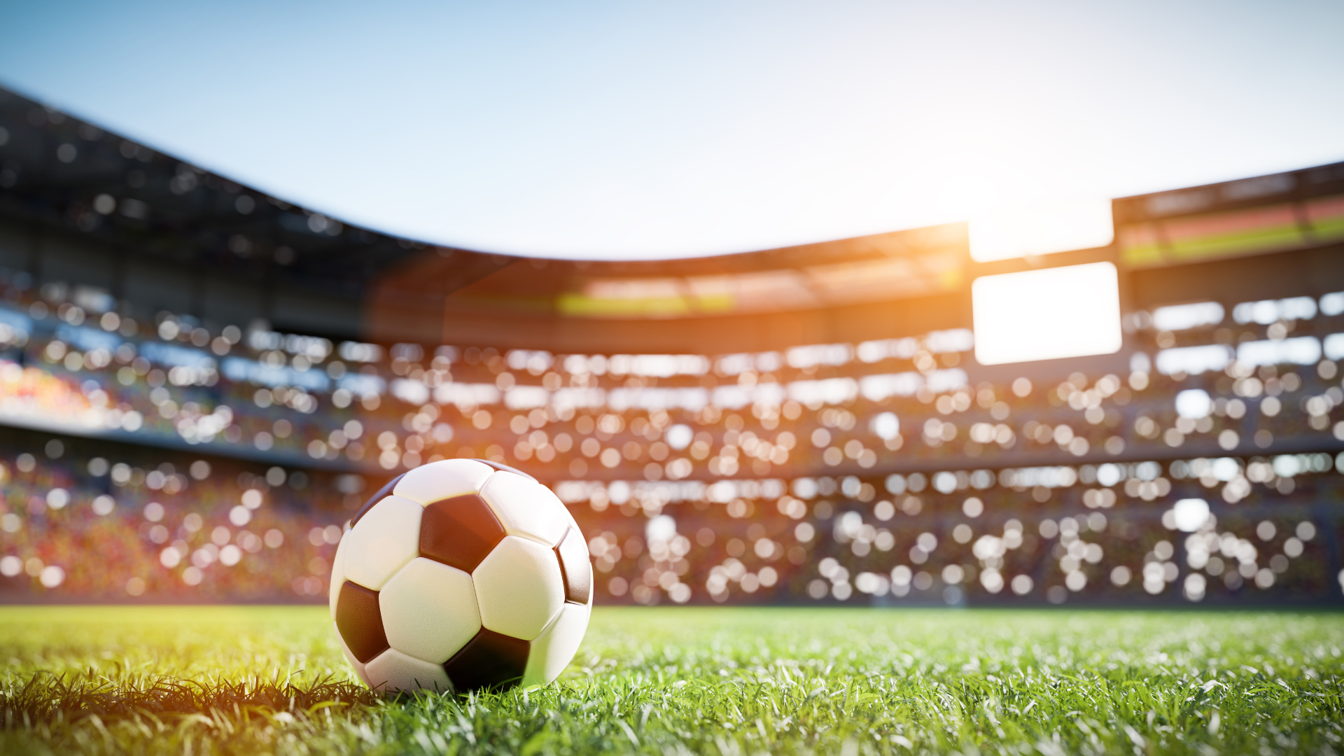 A soccer ball in the field of a filled stadium.