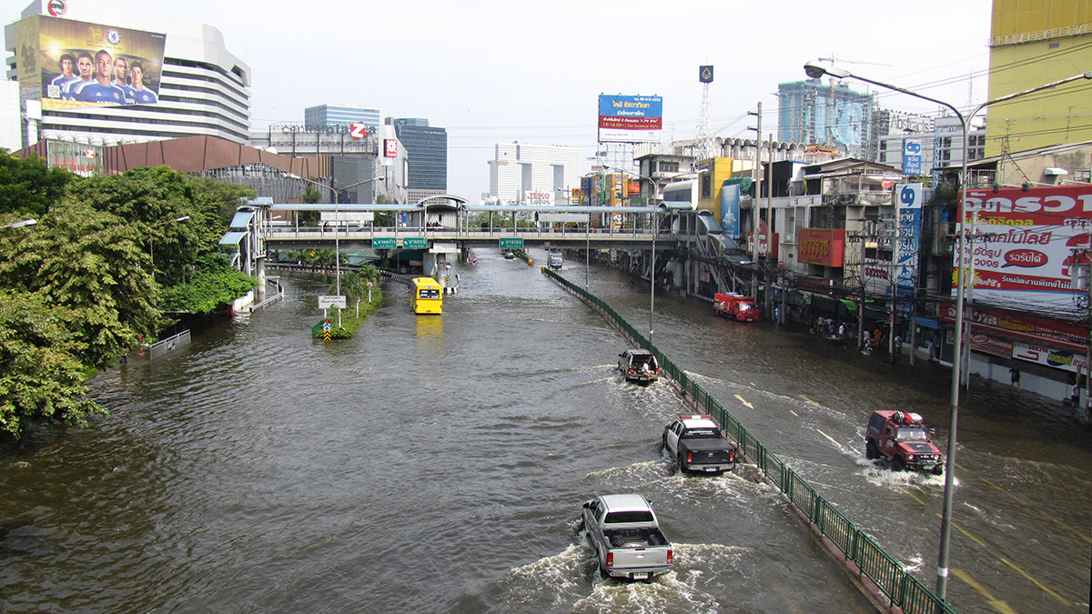 Photo showing flooded city roads in Thailand. Seven vehicles are driving through the flood waters.