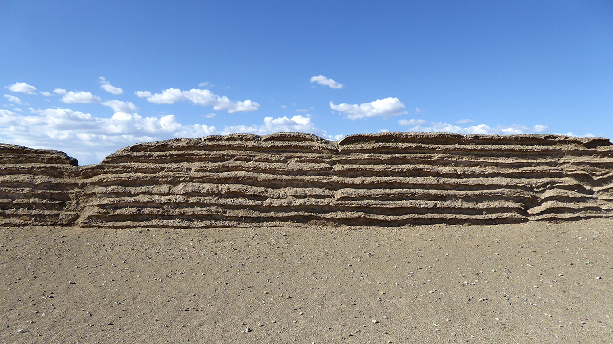 The Han dynasty wall is a brown structure of grass-filled layers.