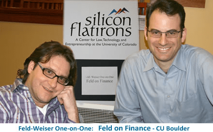 Two men posing for a photo in front of a sign for Silicon Flatirons, which is a center for law, technology, and entrepreneurship at the University of Colorado. The photo emphasizes the 'Feld on Finance' event.