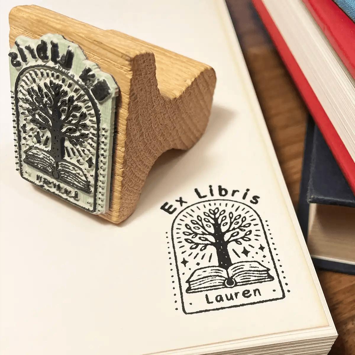 An 'Ex Libris' book stamp next to its impression on a the page of a book.