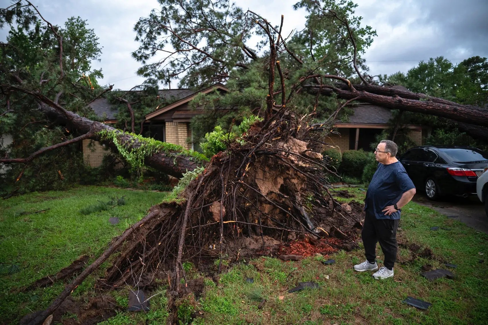 Un hombre cerca del arbol que cayó cerca de su casa.