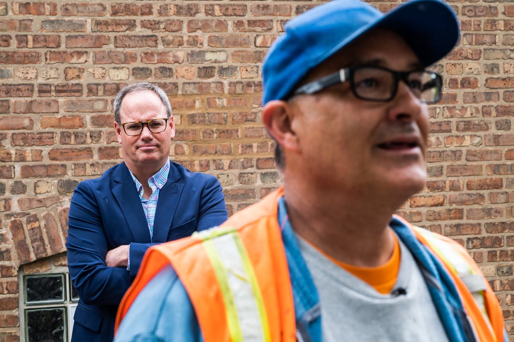 Ald. Marty Quinn (13th) looks on as ward assistant Isidro Rosado talks about his rat abatement work near a Chrysler Village row home on May 19. (Credit: Colin Boyle/Block Club Chicago)
