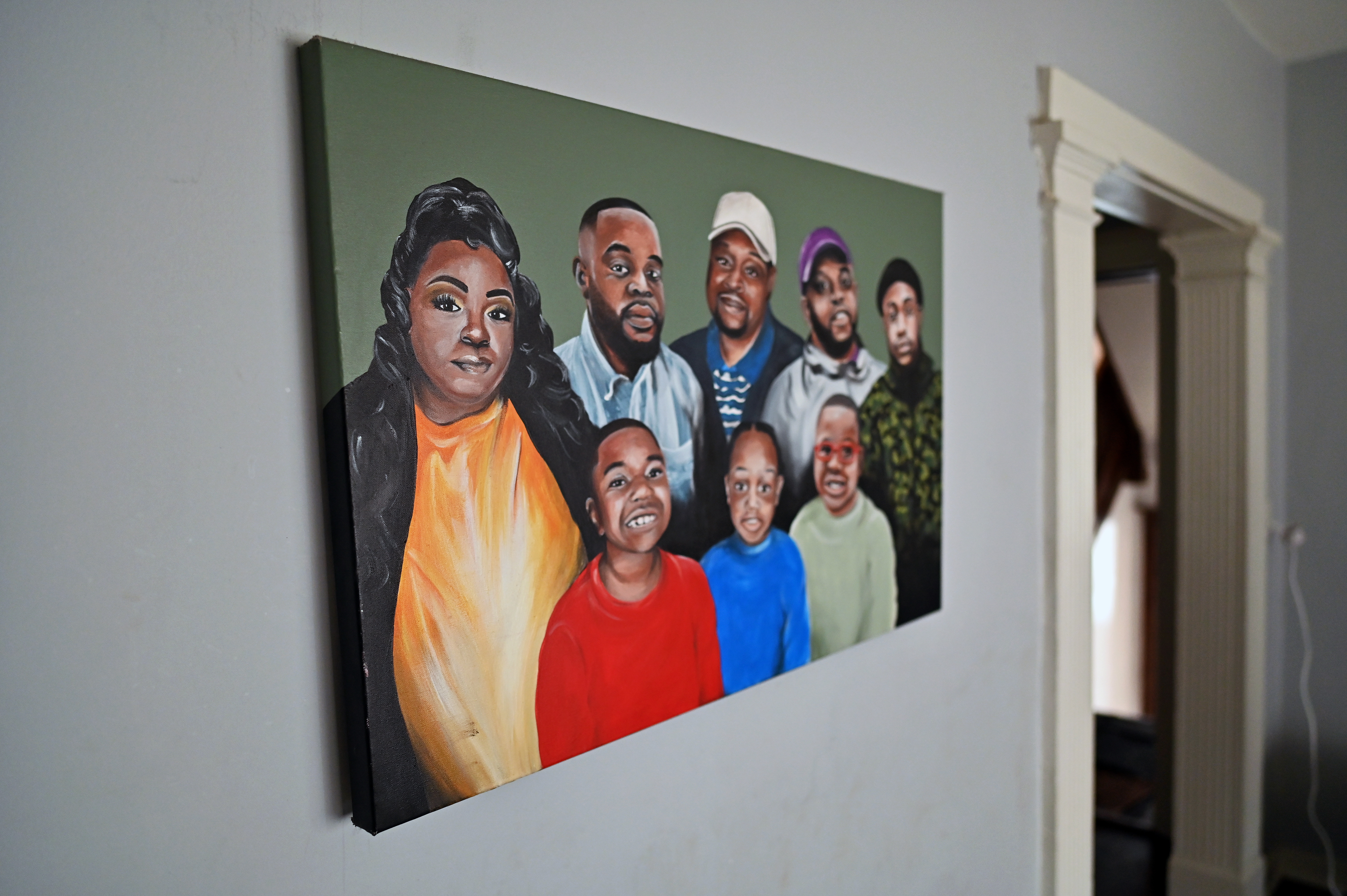 Dominique Henderson’s family portrait in his apartment entryway. Henderson is second to the left in the back row. (Credit: Victor Hilitski/For Illinois Answers Project)