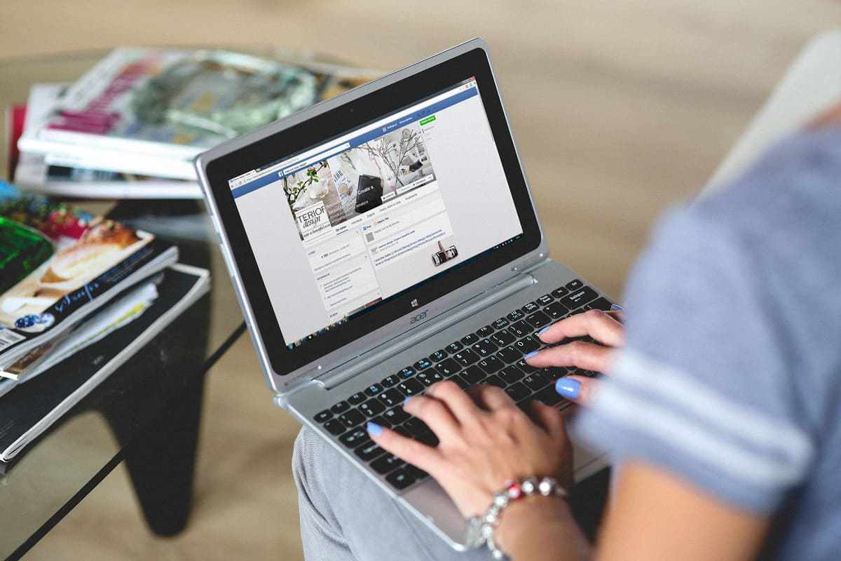 pessoa acessando Facebook: marketing digital mulher sentada com laptop no colo, acessando a página do Facebook