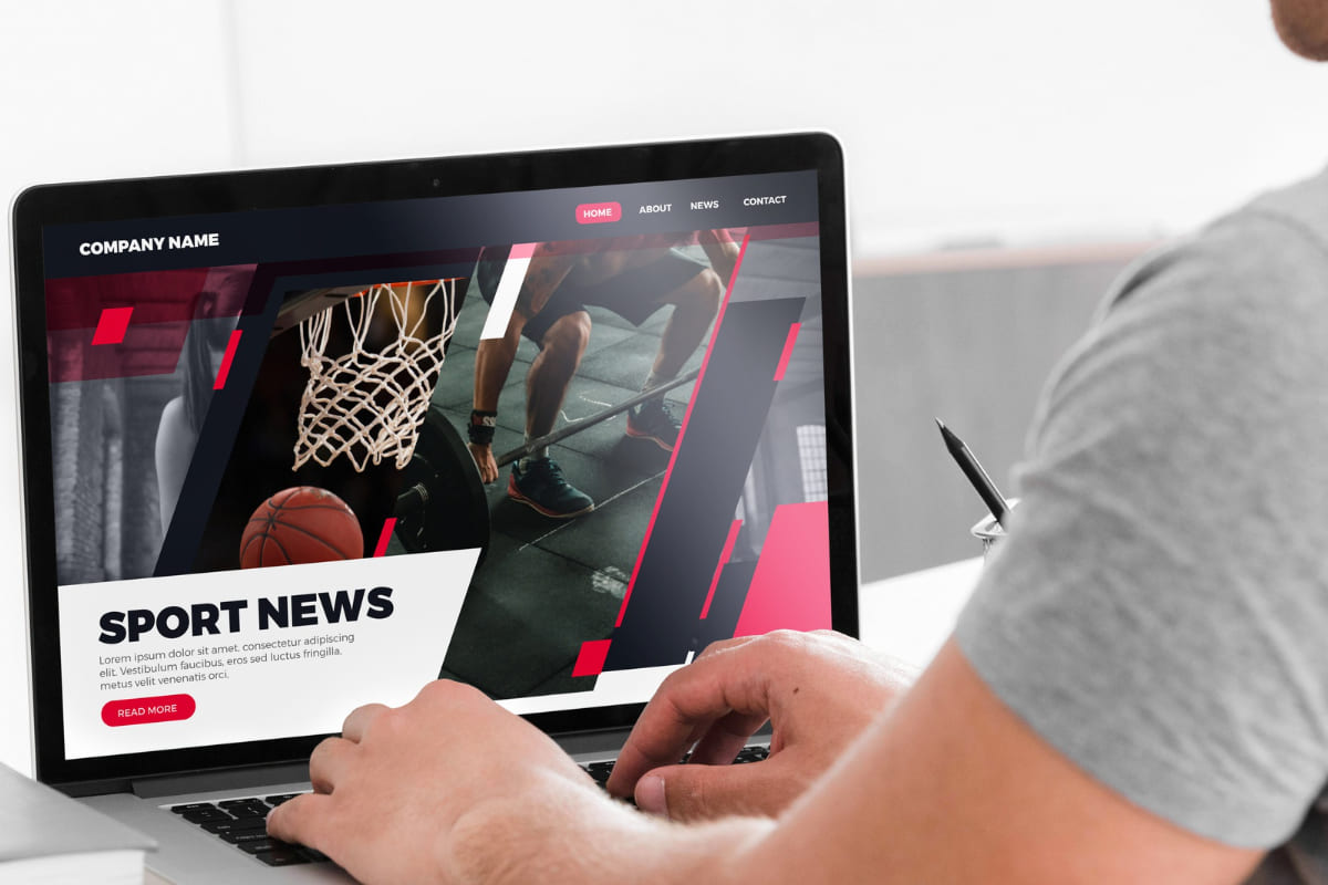 homem usando o laptop: landing page homem sentado usando o laptop com a página de news de esportes aberta