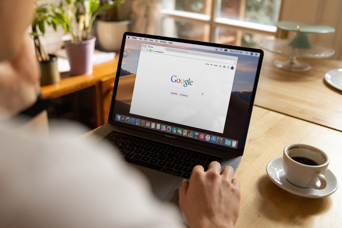 pessoa sentada, usando o laptop com a página inicial do Google aberta
