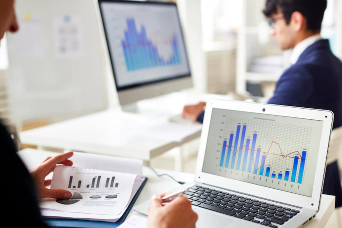 pessoas analisando gráficos: MRR pessoa trabalhando no seu laptop e fazendo anotações em um caderno
