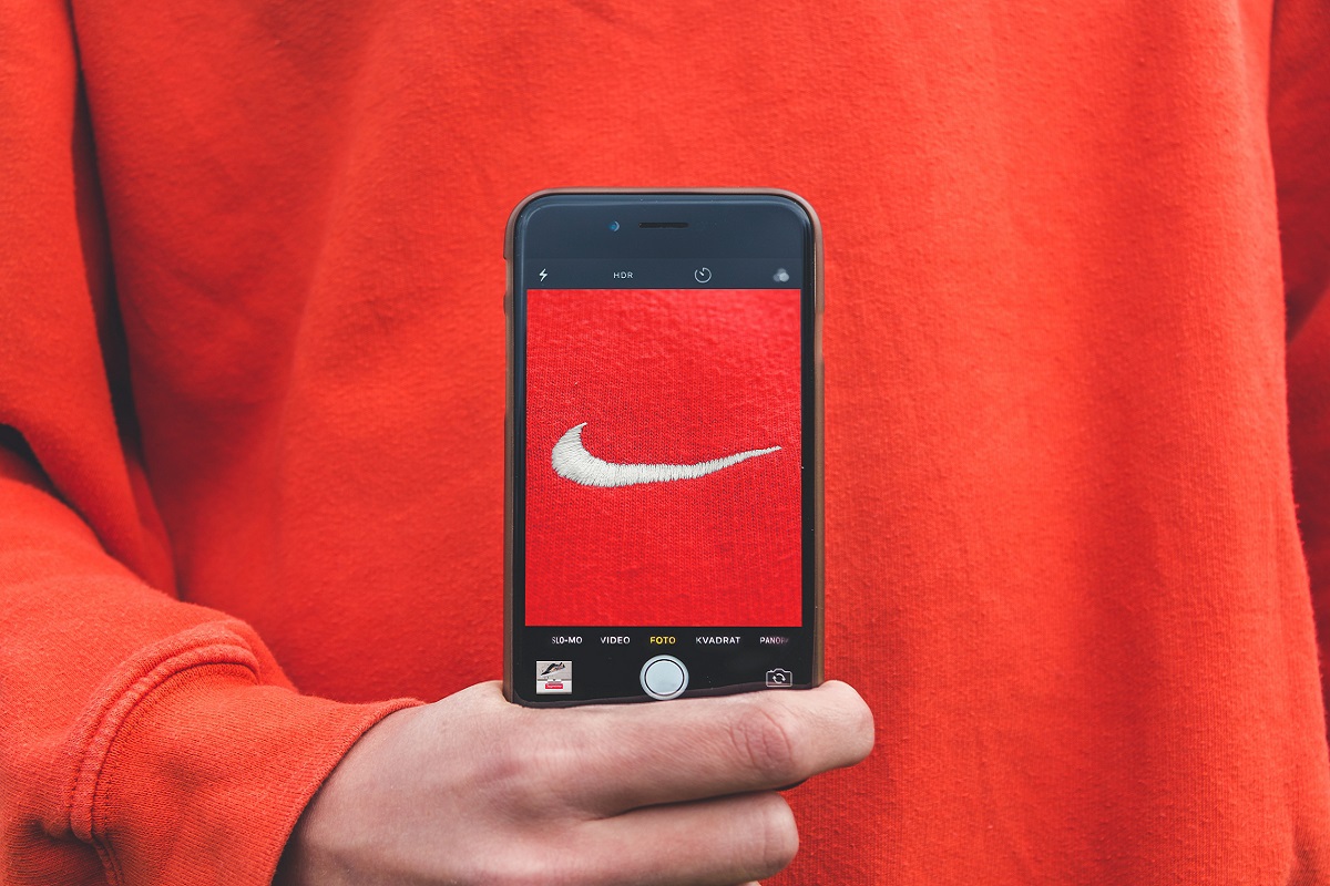homem fotografando a logo da camisa: branding homem usando o celular para fotografar a logo da nike na sua camisa vermelha