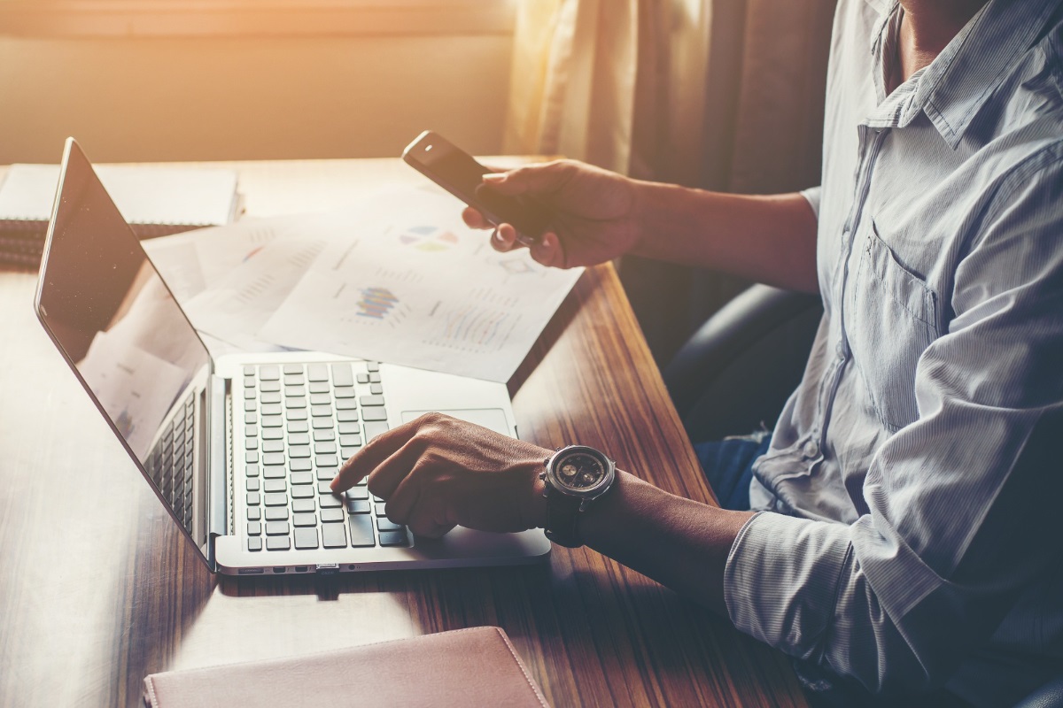 homem trabalhando no laptop e celular: tráfego orgânico homem trabalhando no celular e no laptop ao mesmo tempo