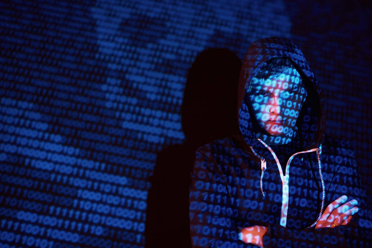 projeção com vários números: black hat imagem de uma pessoa de capuz na frente de uma projeção com vários números