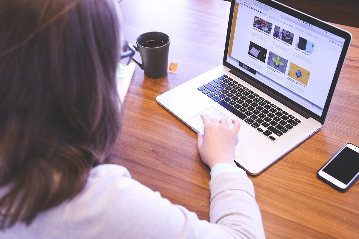 mulher trabalhando no laptop: crt orgânico mulher sentada, trabalhando em seu laptop. Na mesa há também uma caneca de café