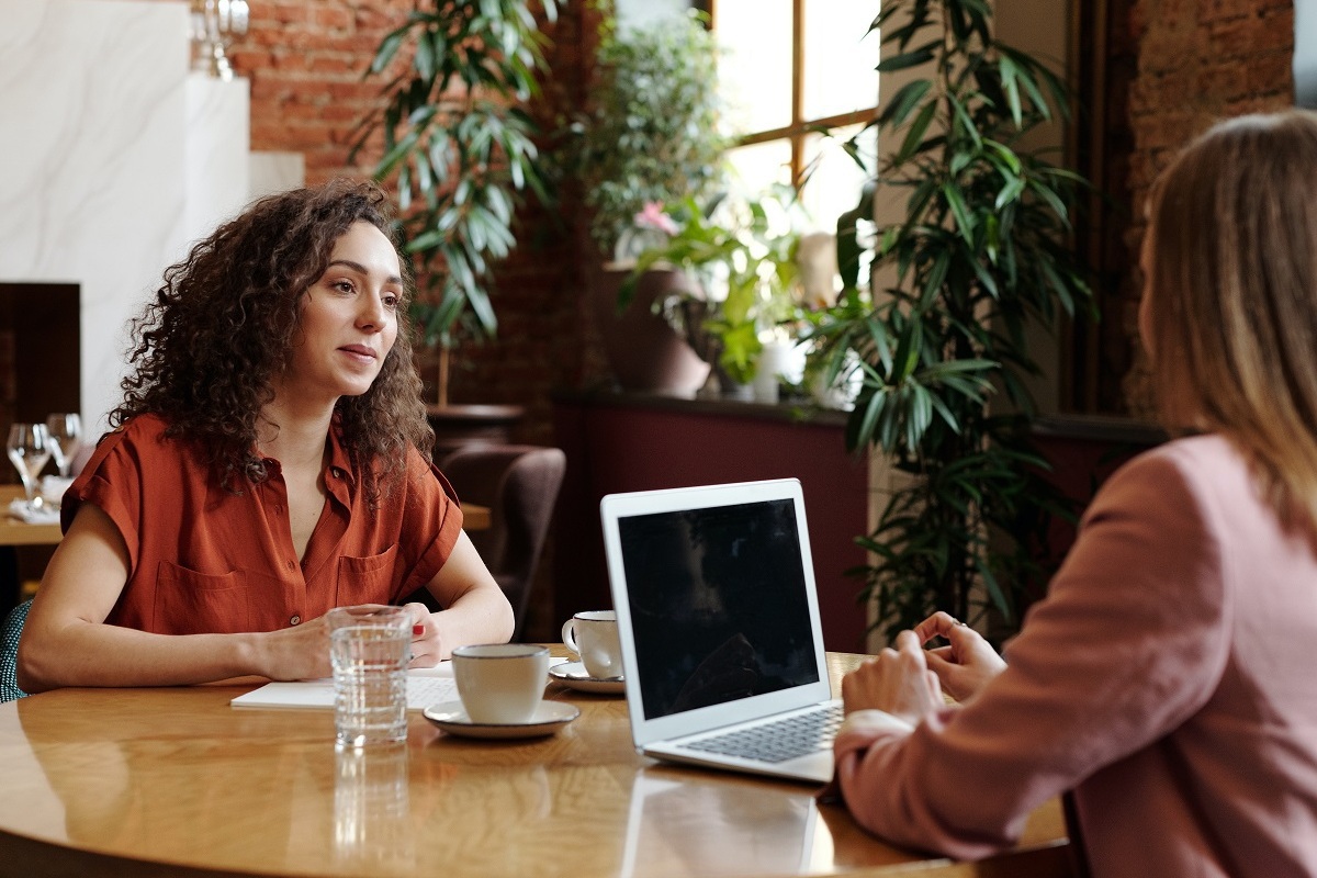 mulheres conversando: feedback duas mulheres conversando, uma delas tem um laptop em cima da mesa