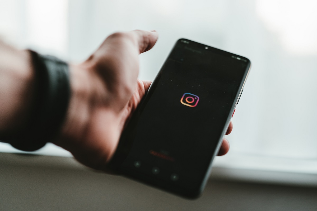 celular abrindo o app do instagram: instagram ads homem com um celular na mão, enquanto abre o app do Instagram
