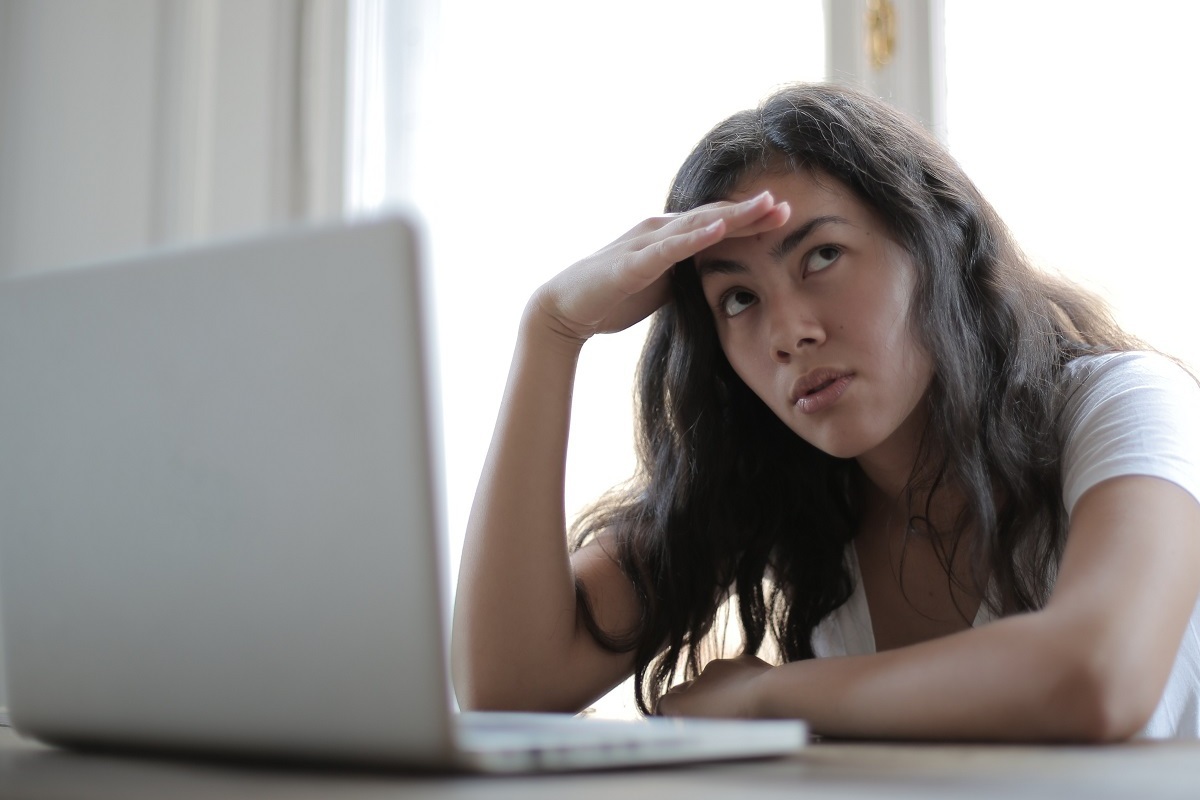 mulher na frente de um laptop: seo técnico mulher sentada em frente a um laptop, com a mão na testa, como se estivesse um tanto estressada
