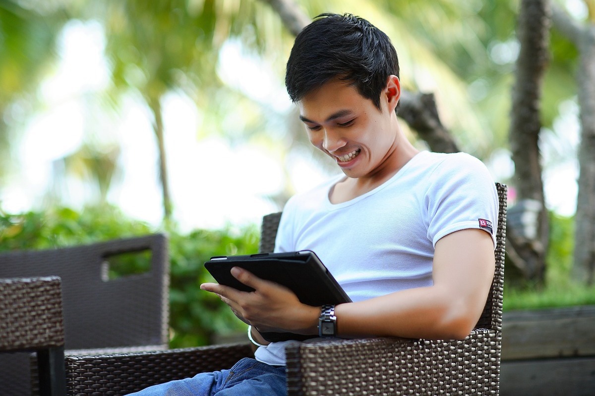 homem usando o tablet: whatsapp business homem sentado, usando o tablet