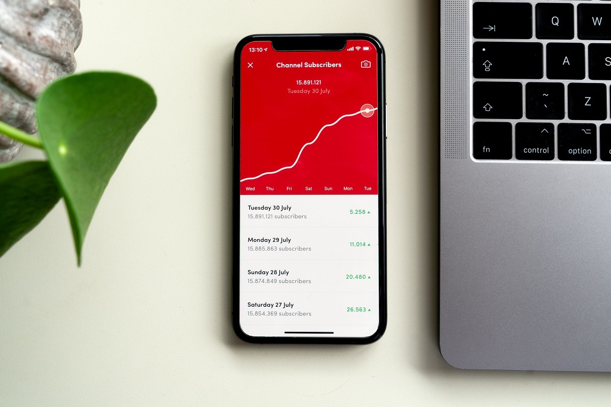 celular mostrando número de inscritos de um canal no youtube: youtube ads celular do lado de um notebook. No celular, a tela está mostrando a quantidade de inscritos em um canal do youtube em forma de gráfico