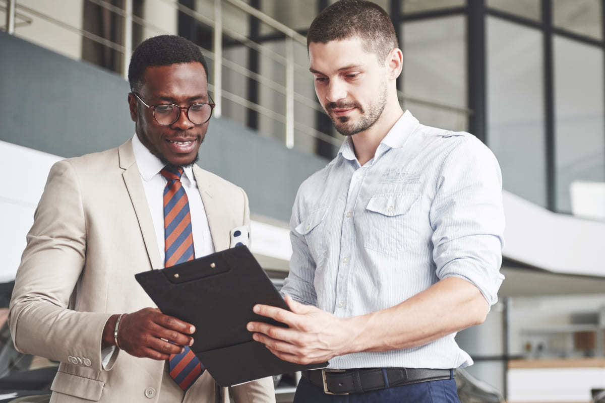 homens de negócio: convencer alguém homens de terno, em pé, olhando para uma prancheta