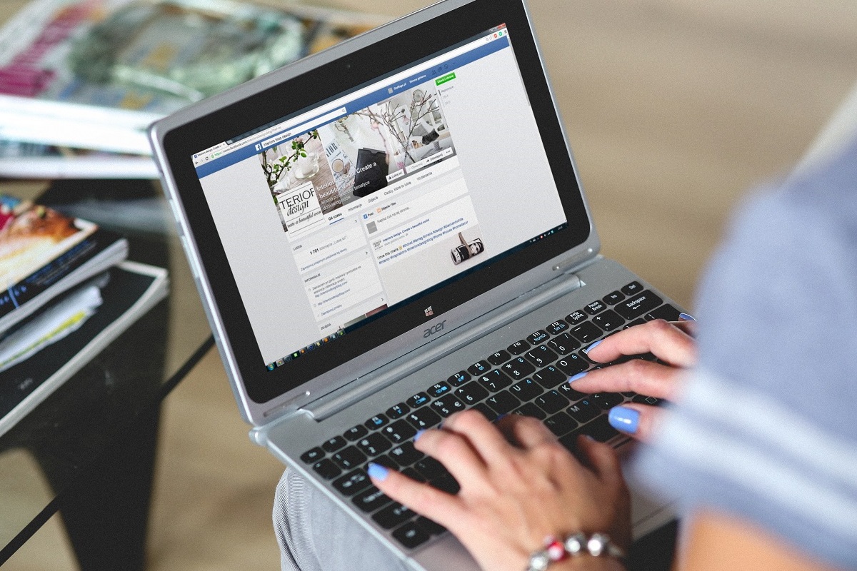 pessoa acessando o facebook: facebook marketplace pessoa sentada, com um notebook no colo, acessando o facebook