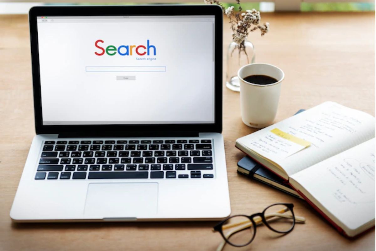 notebook: fatores de rankeamento google notebook em cima da mesa, do lado de um caderno e uma caneca de café