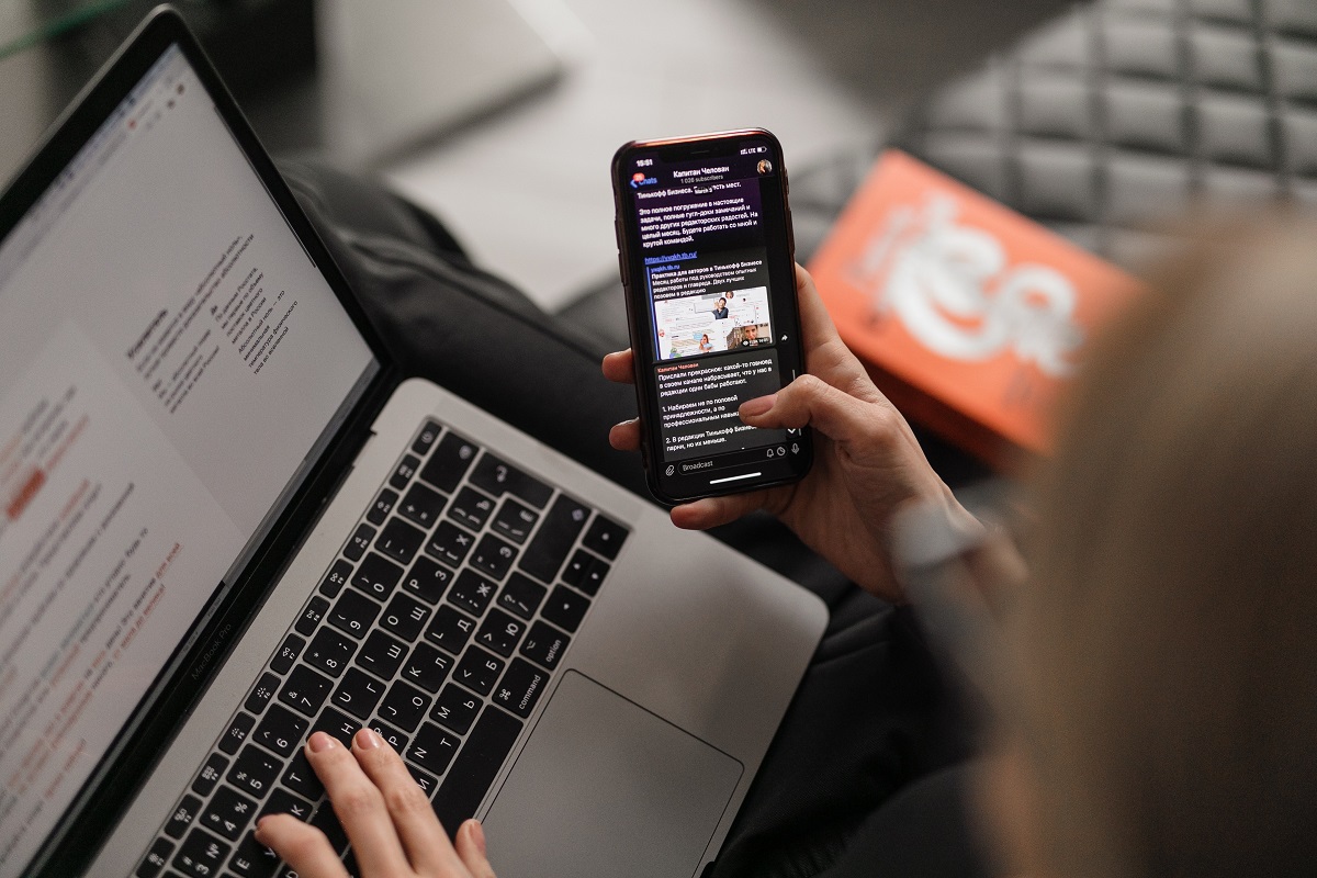 pessoa trabalhando no celular e no laptop: fatores de rankeamento google pessoa sentada, trabalhando em seu laptop e no celular ao mesmo tempo