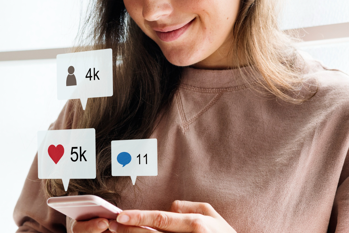 pessoa usando o celular: horário de postagem mulher usando o celular, com vários símbolos perto dele que representam as redes sociais