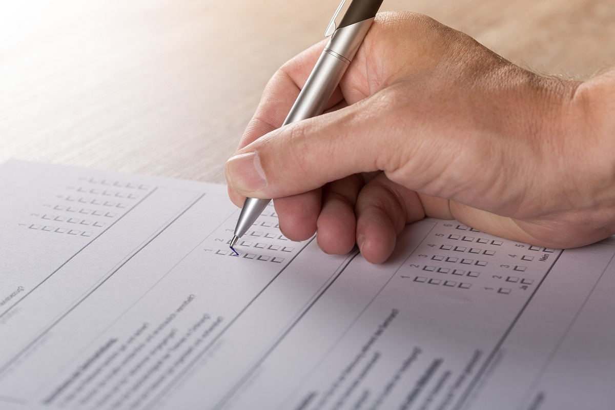 pessoa respondendo formulário: personas pessoa escrevendo em uma folha, parece estar marcando um formulário