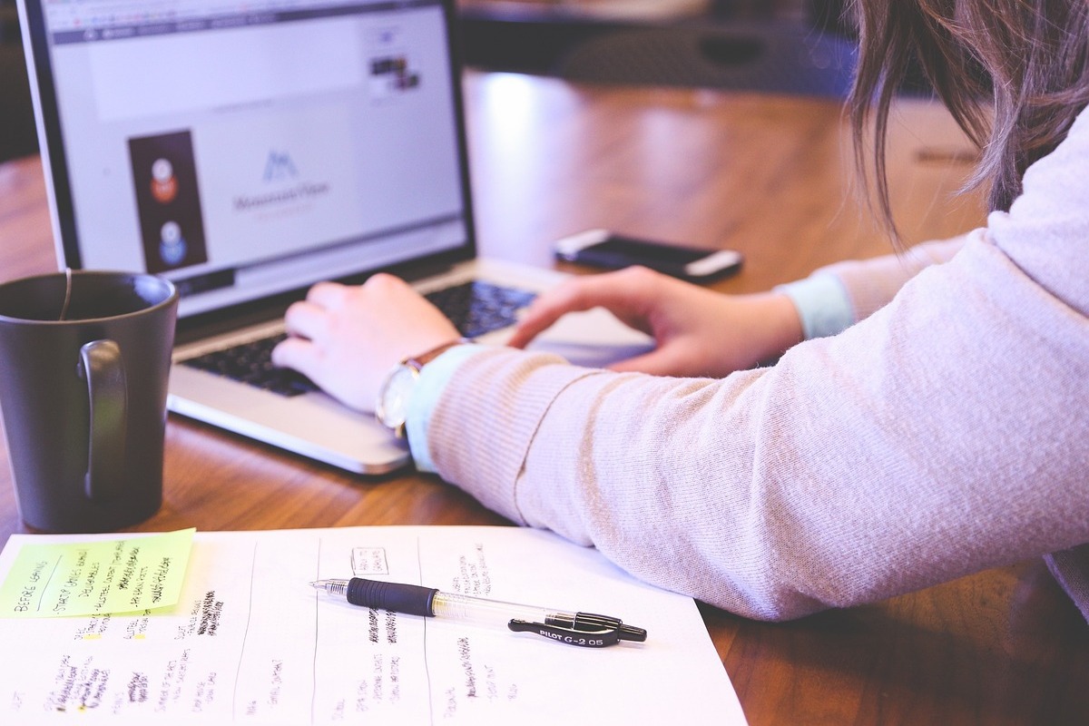 pessoa trabalhando no laptop: personas pessoa sentada, trabalhando em seu laptop, com uma folha de papel do lado