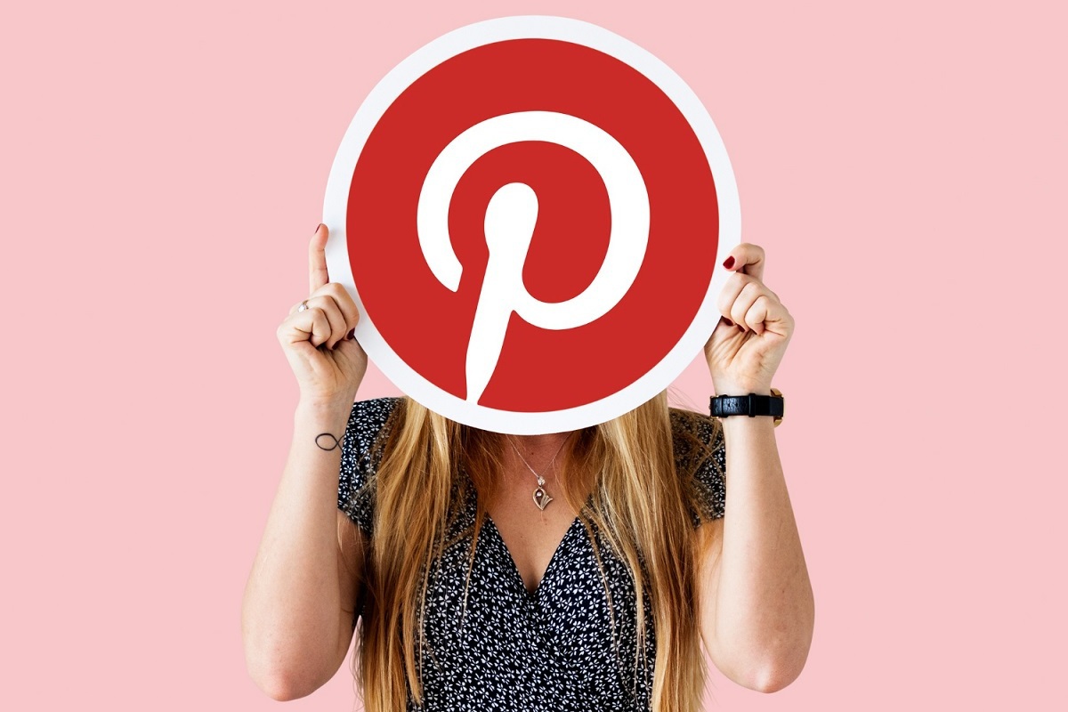 Pinterest: o que é e como usar uma das maiores redes sociais do mundo? mulher segurando um cartaz com o símbolo do pinterest na altura do rosto