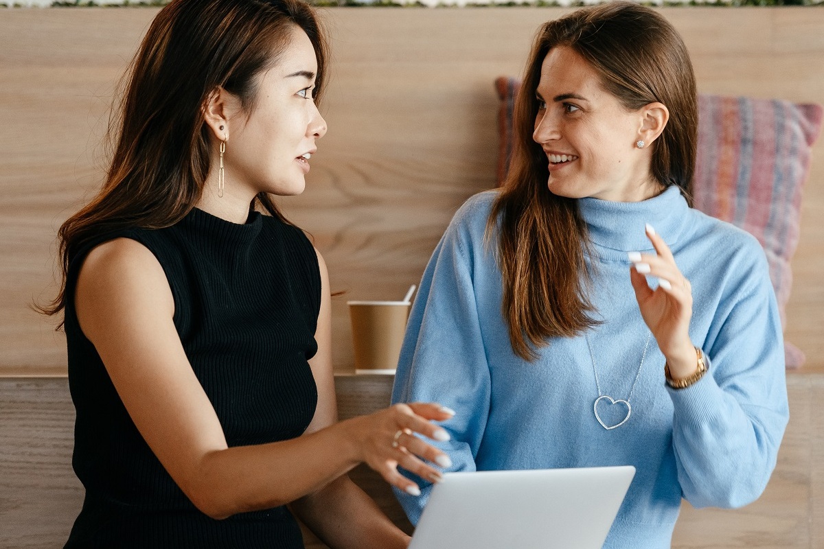 mulheres conversando: script de vendas duas mulheres conversando, enquanto uma delas segura uma folha