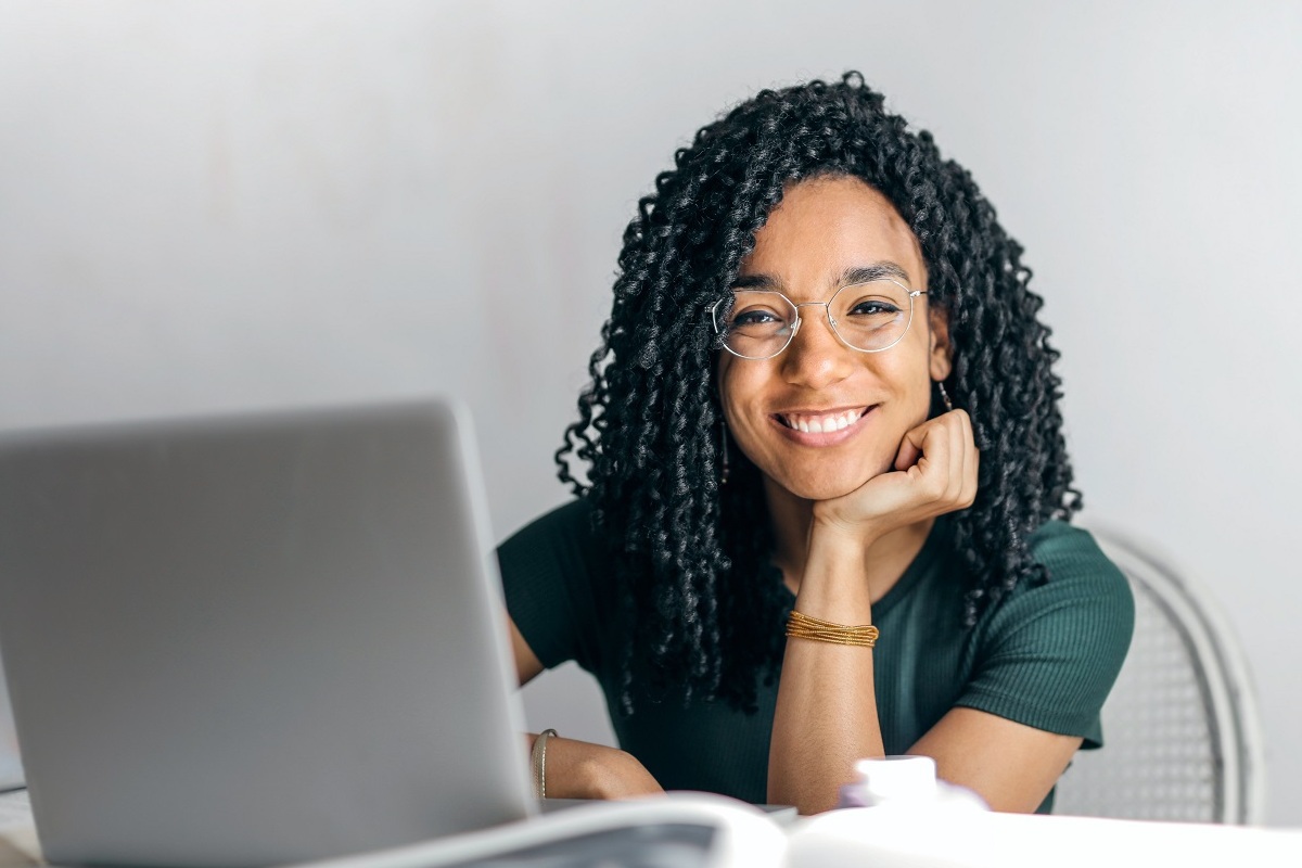 mulher com laptop: social media mulher sentada, sorrindo, com um laptop a sua frente
