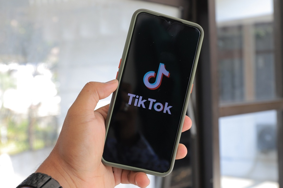 celular: TikTok Ads imagem de uma pessoa segurando o celular mostrando o app do TikTok abrindo