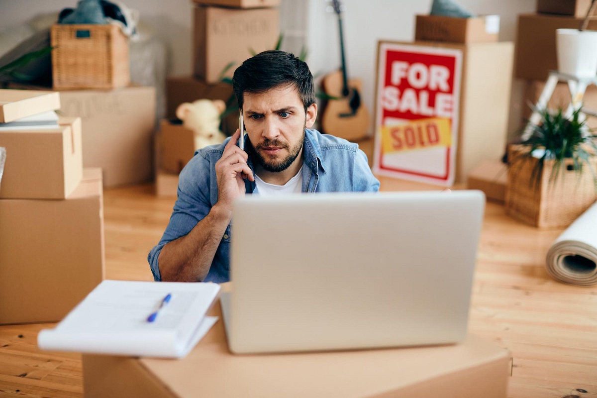 homem trabalhando vendendo: venda consignada homem sentado, falando ao celular, enquanto usa o laptop